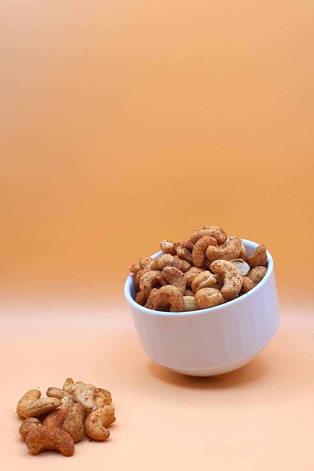 Cashewkerne geröstet mit Pfeffer 1000 g serviert in einer Schale vor neutralem Hintergrund