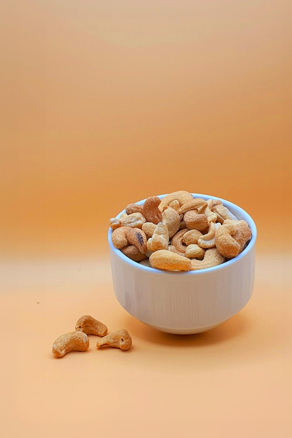 Cashewkerne geröstet und gesalzen serviert in einer Schale vor neutralem Hintergrund